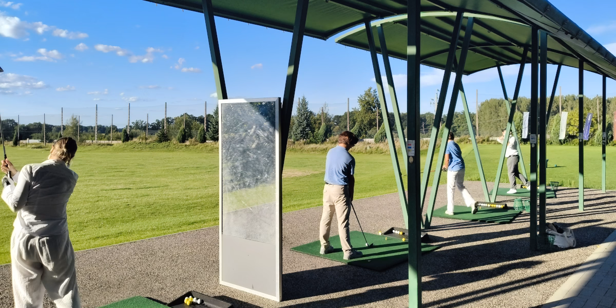 Group of beginners practising golf shots on the driving range