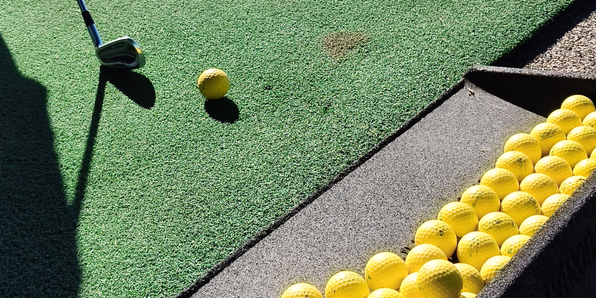 Practice balls and a golf club on a driving range mat