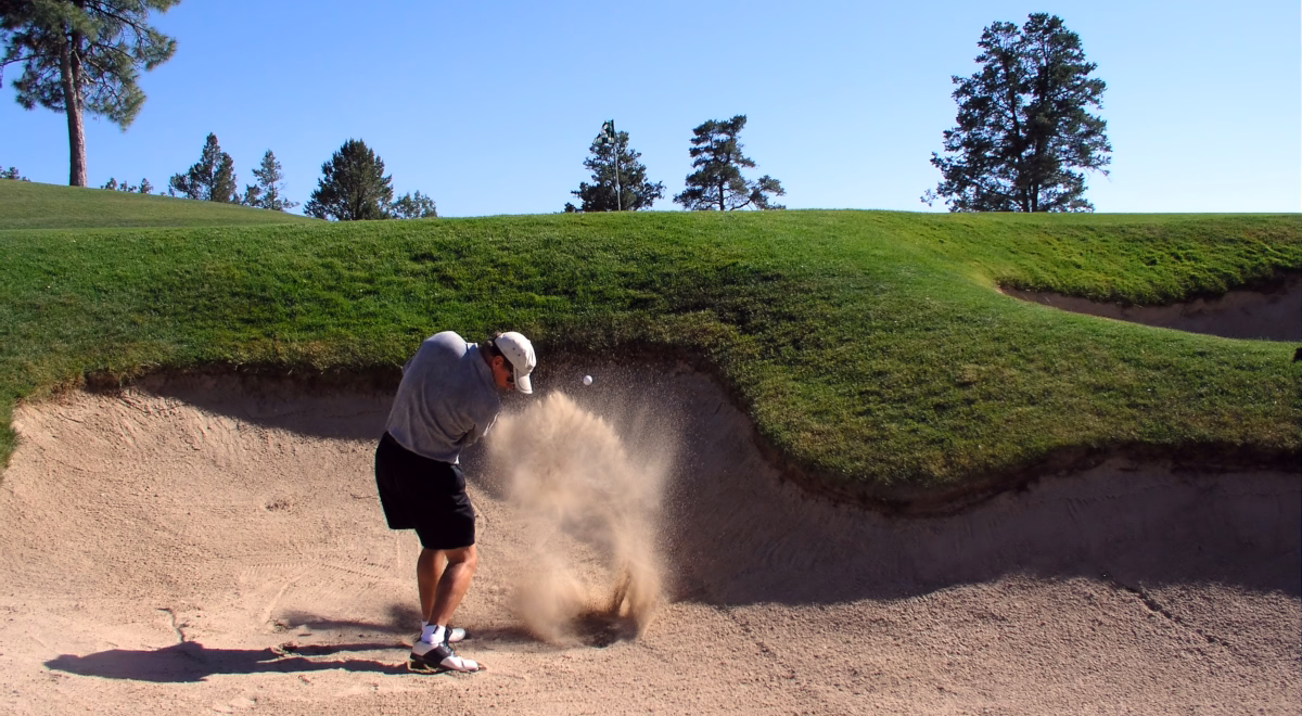 Golfista wybija piłkę z bunkra przy greenie